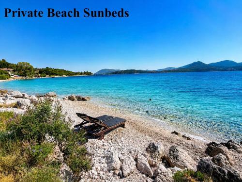 a picnic bench on a beach next to the water at Ciel Seafront Suites - Lefkada in Lygia