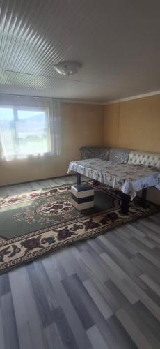 a bedroom with a bed and a rug and a window at Amir Guesthouse in Chon-Dzhargylchak