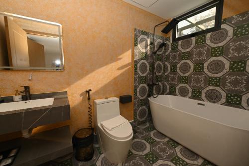 a bathroom with a tub and a toilet and a sink at EcoHouse Boutique Hotel Huế in Hue