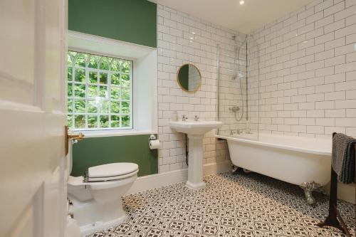 a bathroom with a tub toilet and a sink at Cwmalis Hall in Llangollen
