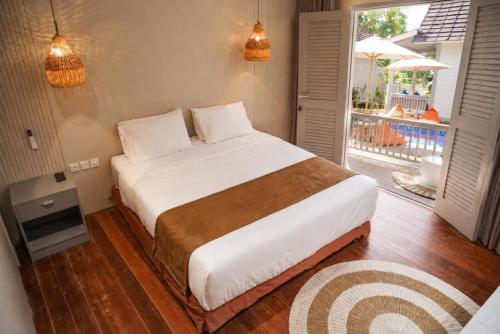 a bedroom with a large bed and a balcony at Hu'u Beach Front Hotel in Gili Trawangan