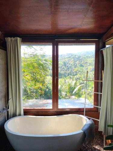 a bath tub in a room with a large window at Aramaya Hills Boutique in Banjar
