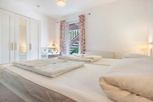 a large white bed in a room with a window at Haus K 104 in Röbel