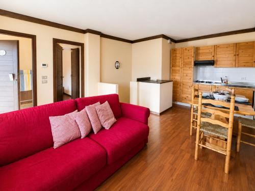 a red couch in a living room with a kitchen at Hostdomus - B4-03 in Grange Sises