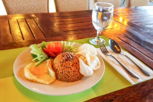 a plate of food on a table with a glass of wine at Hotel O Padang City Center Near Pantai Padang Formerly D'Dhave Hotel in Padang