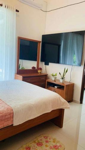 a bedroom with a bed and a flat screen tv at Prime Lake Villa in Kundasale