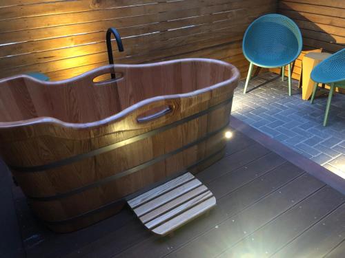 a wooden bath tub with two chairs and a bench at Avero in Rotorua