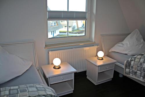 a room with two beds and two tables with lamps at Seestern in Dranske