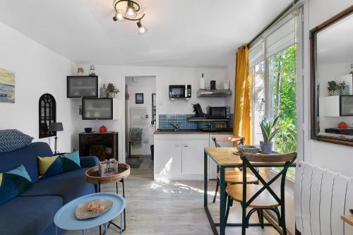 a living room with a blue couch and a table at Le Petit Bécot De Paimpol in Paimpol
