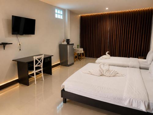 a bedroom with two beds and a desk and a television at Ruen Aiyara Apartment in Nakhon Ratchasima