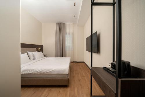 ein Schlafzimmer mit Bett und Flachbildfernseher in der Unterkunft Fly Inn Hotel in Vragolija