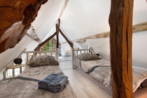 two beds in a attic bedroom with wooden floors at Gîte Ressources - Jacuzzi in La Frenaye