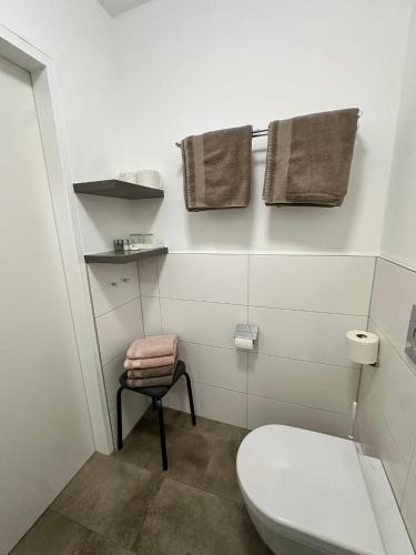 a bathroom with a toilet and a stool and towels at Appartement Marlene in Maishofen
