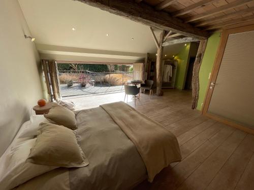 a large bed in a room with a large window at Authentique gite de village in Hotton