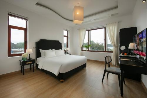 a bedroom with a white bed and a desk and windows at Maison Bay View Villa Cat Ba in Ðồng Khê Sâu