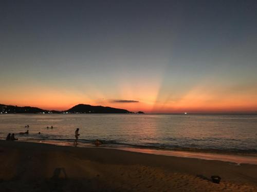 a group of people on the beach at sunset at Baan Andaman Sea Surf in Patong Beach