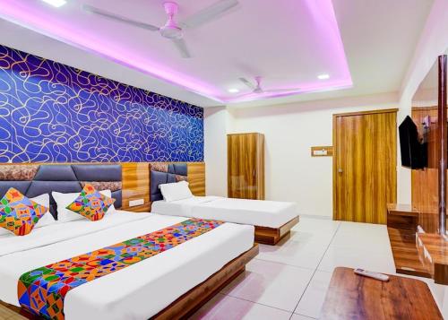 a bedroom with two beds and a blue wall at Hotel Lakeview Vadodara in Vadodara