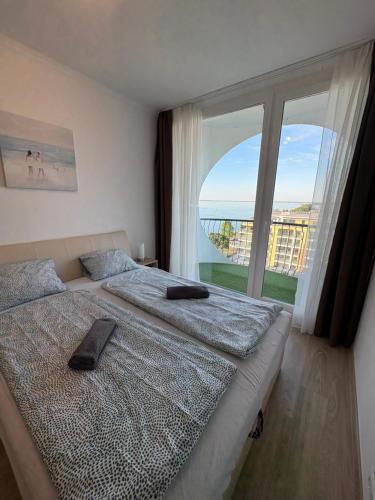 a bedroom with two beds and a large window at Seaforth Apartment in Siófok
