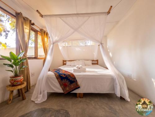 a bedroom with a white bed with a canopy at Consul's House Vilanculos in Vilanculos