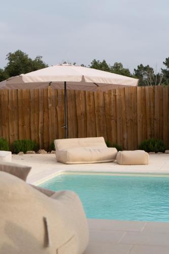 an umbrella and pillows next to a swimming pool at Casa Fonte da Telha in Santiago do Cacém