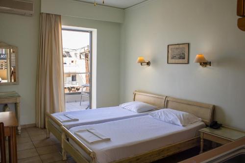 a bedroom with a bed and a large window at Jason Hotel Apartments in Rethymno