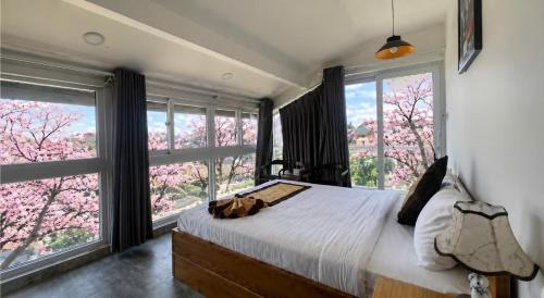 a bedroom with large windows and a bed with a white bedspread at Cherry Luxury Hotel in Da Lat