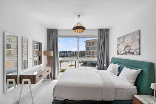 a bedroom with a bed and a desk and a window at Marassi Marina Views At BirdNest in Sīdī ‘Abd ar Raḩmān