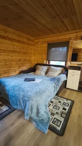 a bedroom with a bed with a blue blanket on it at Vasarnīca Pie Anniņas in Pasteri