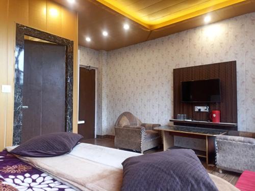 a bedroom with a bed and a tv and a couch at Hotel Pine View Villa in Dagshai