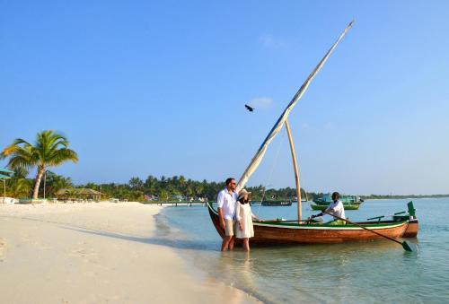 two people standing on the beach next to a boat at Nolhi Escape in Nolhivaranfaru