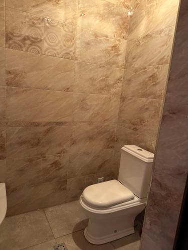 a bathroom with a toilet and a tiled wall at Dom in Aygavan