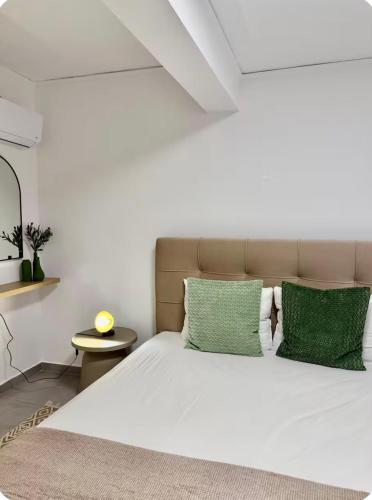 a bedroom with a white bed with green pillows at Aegean Horizon Seafront Luxury Villa Plomari Garden Level in Trýgonas