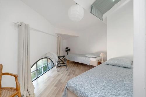 a white room with two beds and a window at Gite Du Cerisier - Varennes in Varennes
