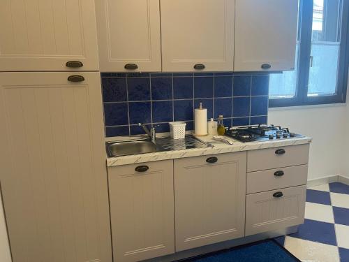 a kitchen with white cabinets and a sink at Dimora Patrizia in Scario