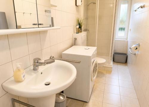 a white bathroom with a sink and a toilet at FeWo kleine Auszeit in Cuxhaven
