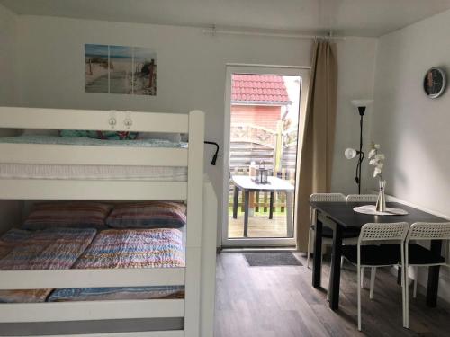 a bedroom with a bunk bed and a table and a dining room at FEWO Kliff Watt Nr.4 in Cuxhaven