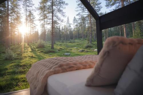 a bed in a tent with a view of a forest at Sāmeland Retreat, Mirrored Glass Cabins, Swedish Lapland in Arvidsjaur