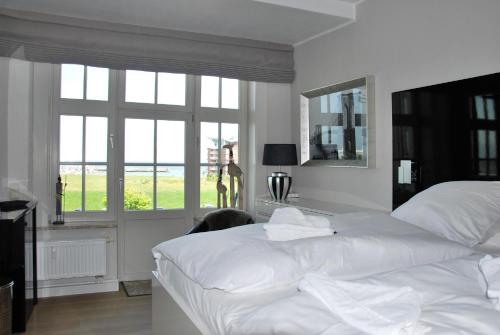 a white bedroom with two beds and a window at Am Seedeich 7 SE10 Seesicht in Cuxhaven