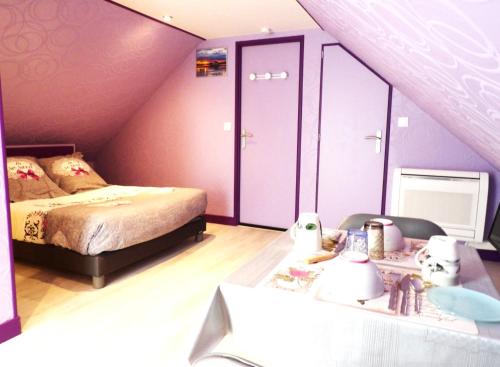 a attic bedroom with a bed and a table with a table at Les ANGES DE SAINTE ANNE in Plumergat