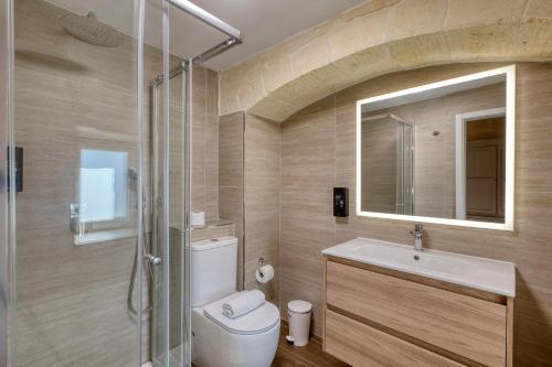 a bathroom with a toilet and a sink and a mirror at Kikka Holiday Home in Xagħra