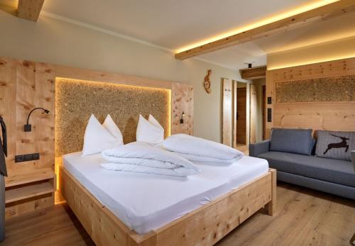 a bedroom with a bed with white pillows and a couch at Das Eppensteiner in Navis