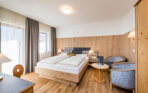 a bedroom with a bed and a table and chairs at Hotel Oberbrunn in Natz-Schabs