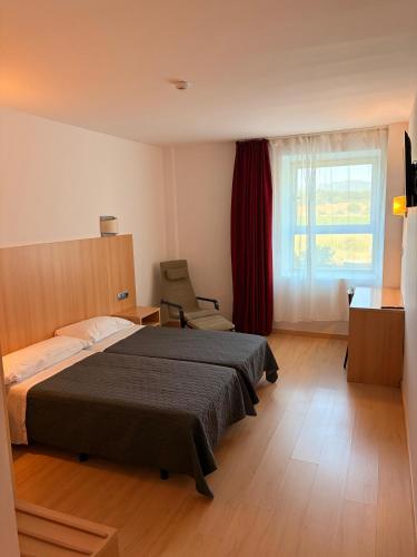 a bedroom with a bed and a chair and a window at Hotel del Vino in Cariñena
