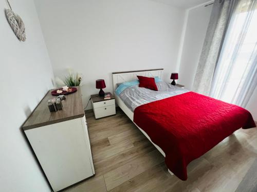 a bedroom with a bed with a red blanket and a desk at Łebska ostoja in Żarnowska