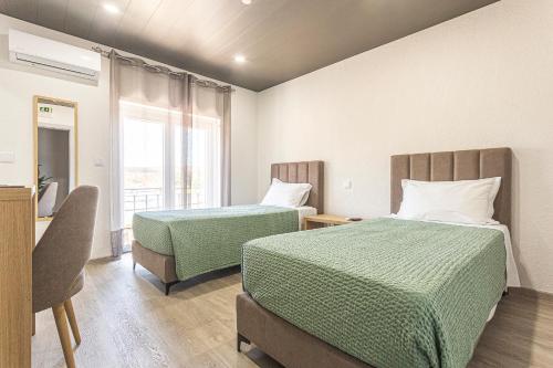 a hotel room with two beds and a window at Flôr do Távora in Vila da Ponte