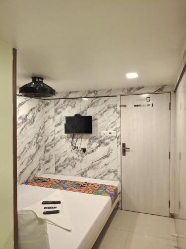 a bedroom with a bed and a tv on a wall at Venus Guest House in Mumbai