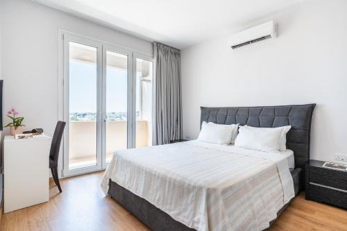 a bedroom with a bed with white sheets and a window at Limassol Marina Seaview Suite in Limassol