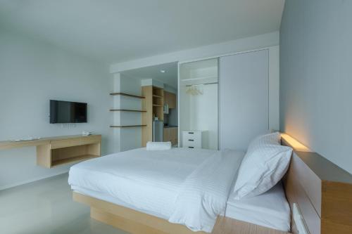 Un dormitorio blanco con una cama y un televisor. en Thongchen Residence, en Samut Sakhon