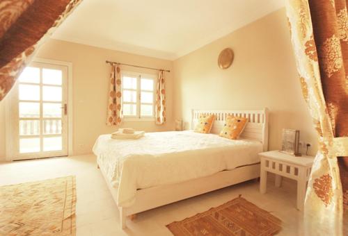 a bedroom with a white bed and two windows at TigerLounge in Douaïra