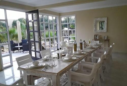 a dining room with a long table and white chairs at TigerLounge in Douaïra